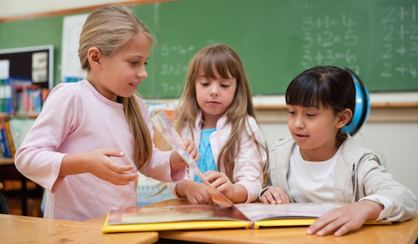 Little schoolgirls reading a fairy tale to their classmate