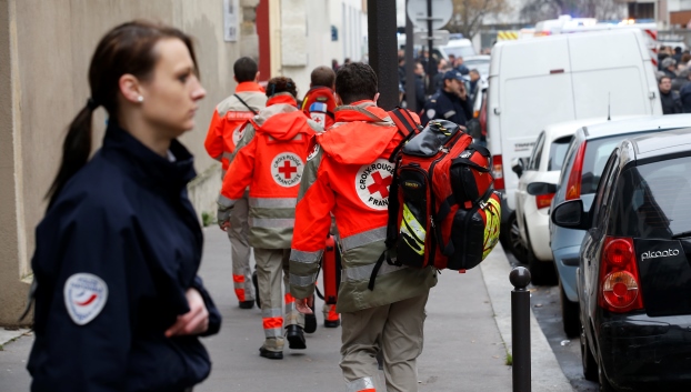 Firefighters and police officers gather in front of the offices of the French satirical newspaper Charlie Hebdo in Paris, France, on January 7, 2015. Gunmen have attacked the Paris office of French satirical magazine Charlie Hebdo, killing 12 people and injuring seven, French officials say. At least two masked attackers opened fire with assault rifles in the office and exchanged shots with police in the street outside before escaping by car. President Francois Hollande said there was no doubt it had been a terrorist attack