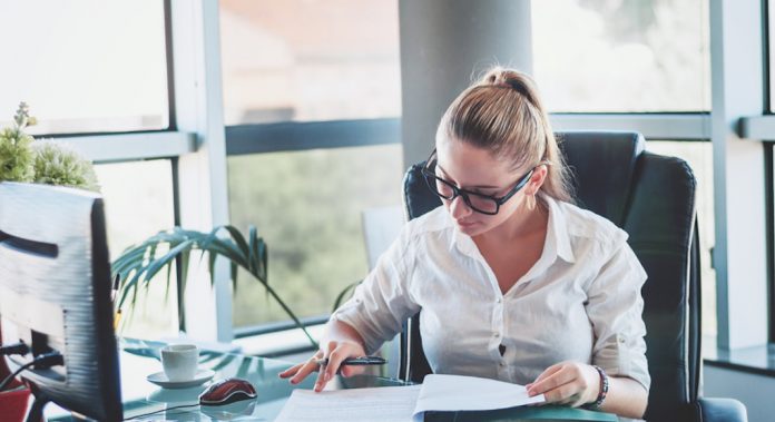 Office worker. Young businesswoman using calculator and laptop for calaulating finance, tax, accounting, statistics and analytic research concept.