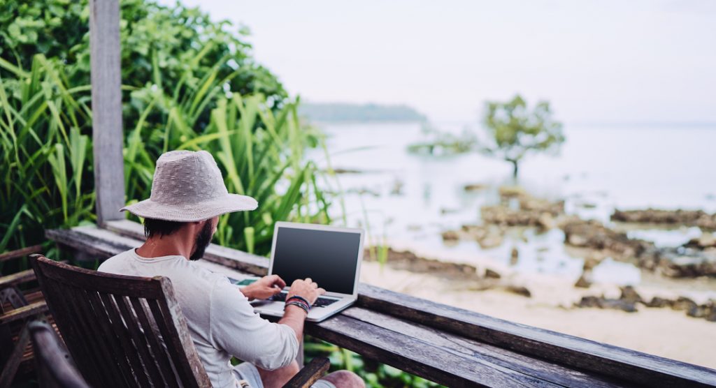 Un homme travaille sur son ordinateur en face de la mer