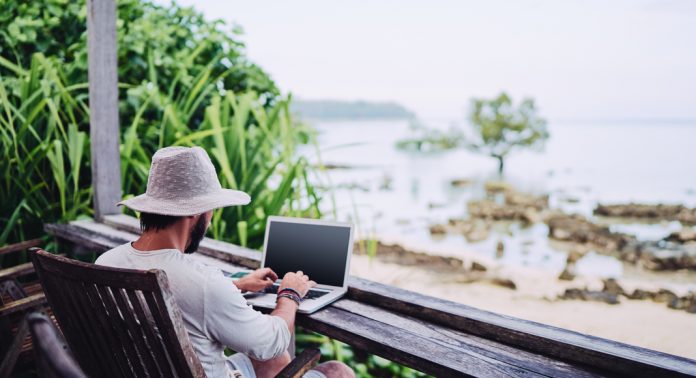 Teletravail_DigitalNomade_FM Un homme travaille sur son ordinateur en face de la mer